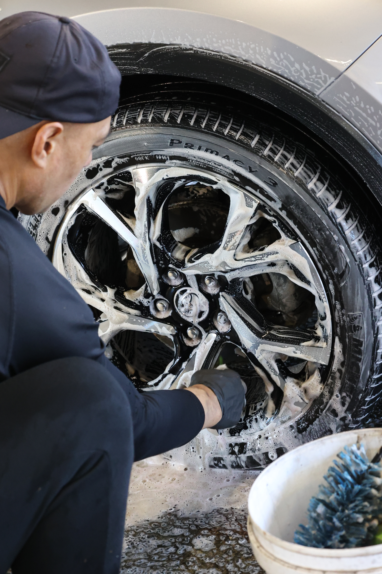 Carfē technician deep-cleaning a soapy alloy wheel