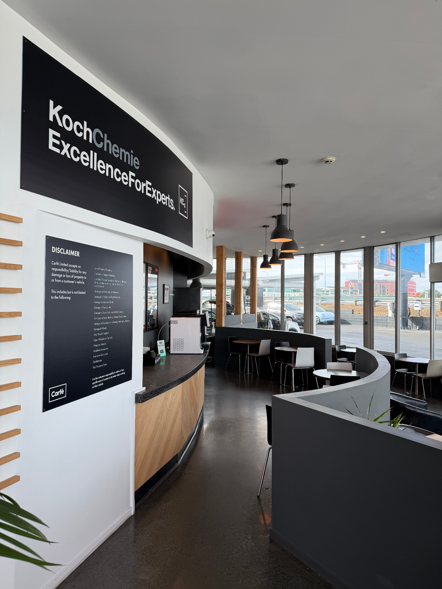 Interior of the Carfē lounge with café seating and Koch-Chemie signage
